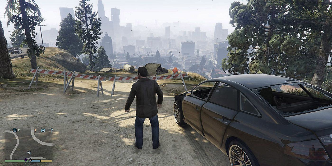Michael nhìn ra thành phố trong Grand Theft Auto 5, đứng cạnh một chiếc ô tô trên đường núi.