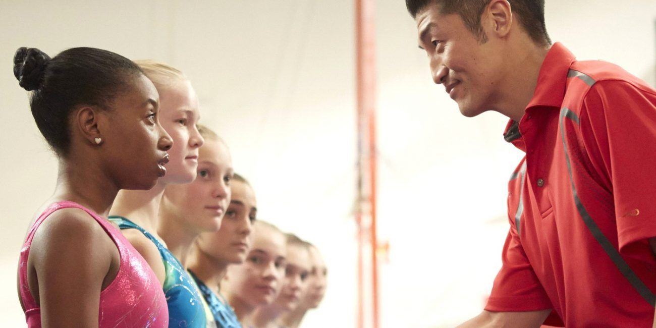 Gabby Douglas stood with a group of other girls as her coach smiled and talked to her.