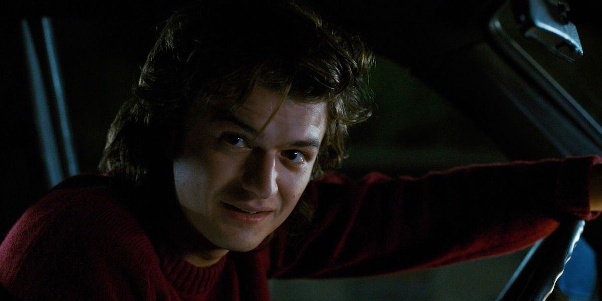 Stranger Things' Steve Harrington leans forward in the car and looks out the window