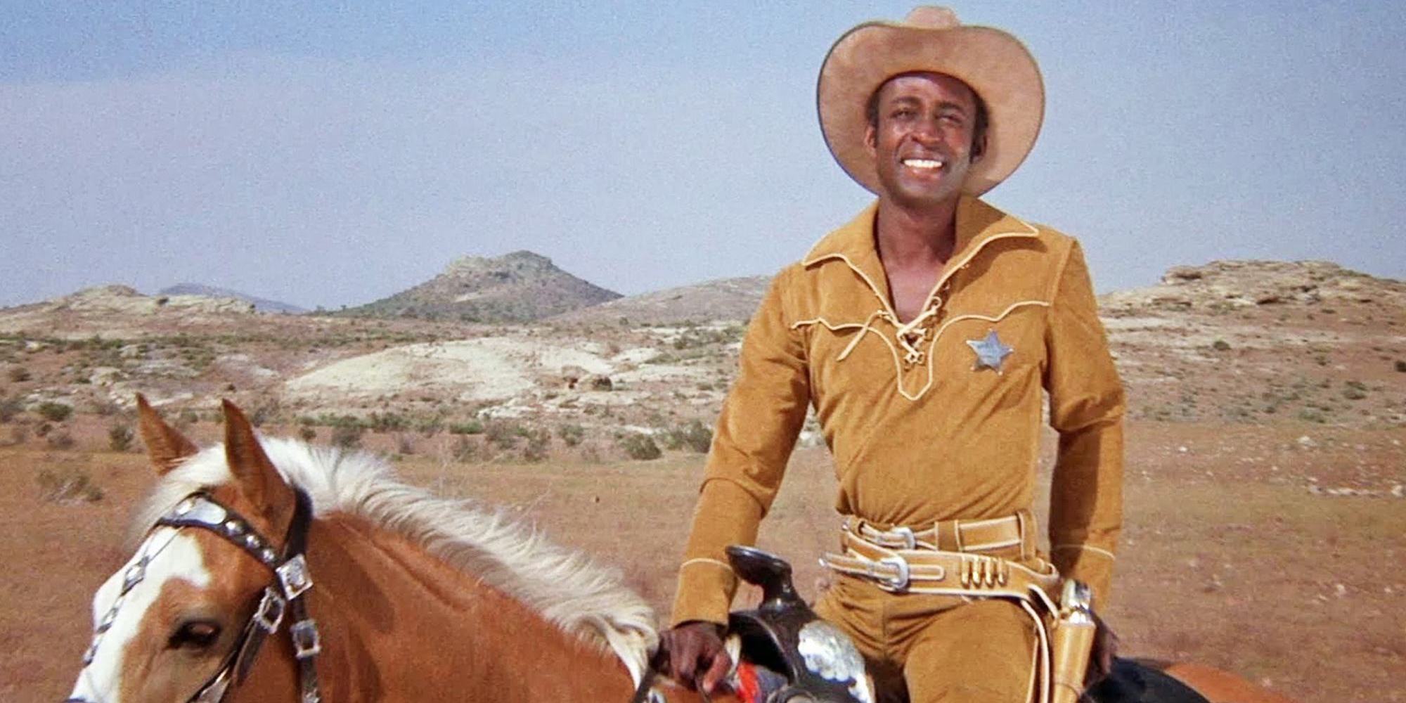 Little Cleavon riding a horse in a sheriff's uniform and smiling with a flaming Saddle on