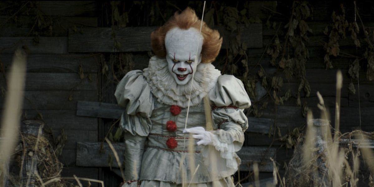 Pennywise (Bill Skarsgard) staring menacingly from the backyard holding a balloon