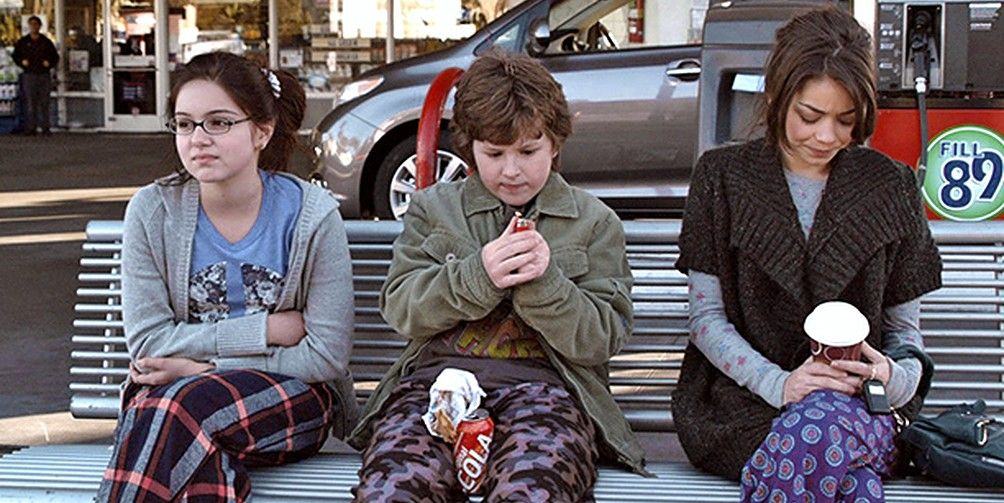 The three Dunphy kids sitting at a gas station bench