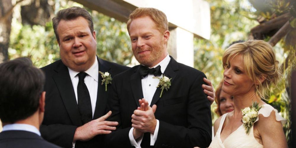 An image of Cam, Mitch, and Claire smiling in Modern Family