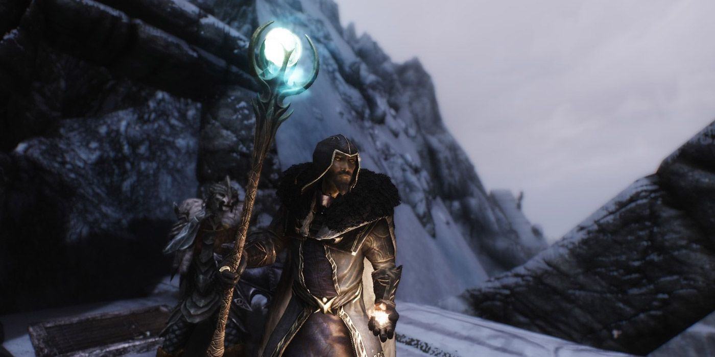 A player in mage robes holding the Staff of Magnus in Skyrim.