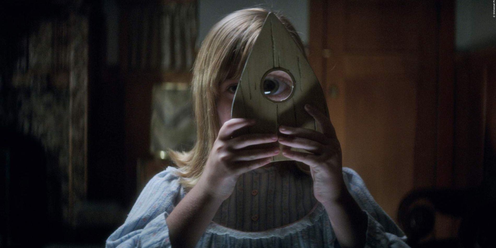 A girl looking through the Ouija board in Ouija: Origins of Evil